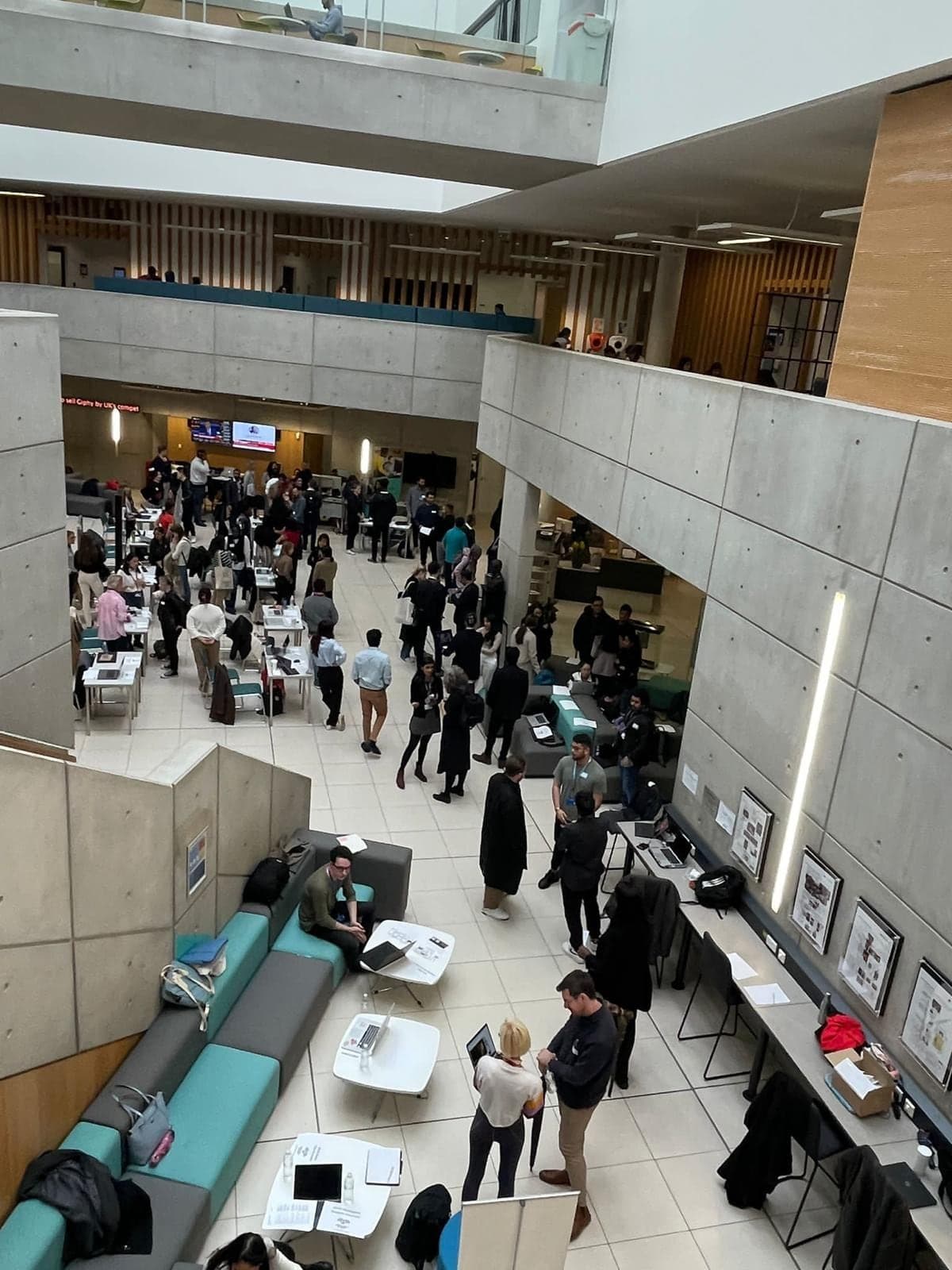 A university atrium filled with students and visitors at a Digital Influx Academy showcase.