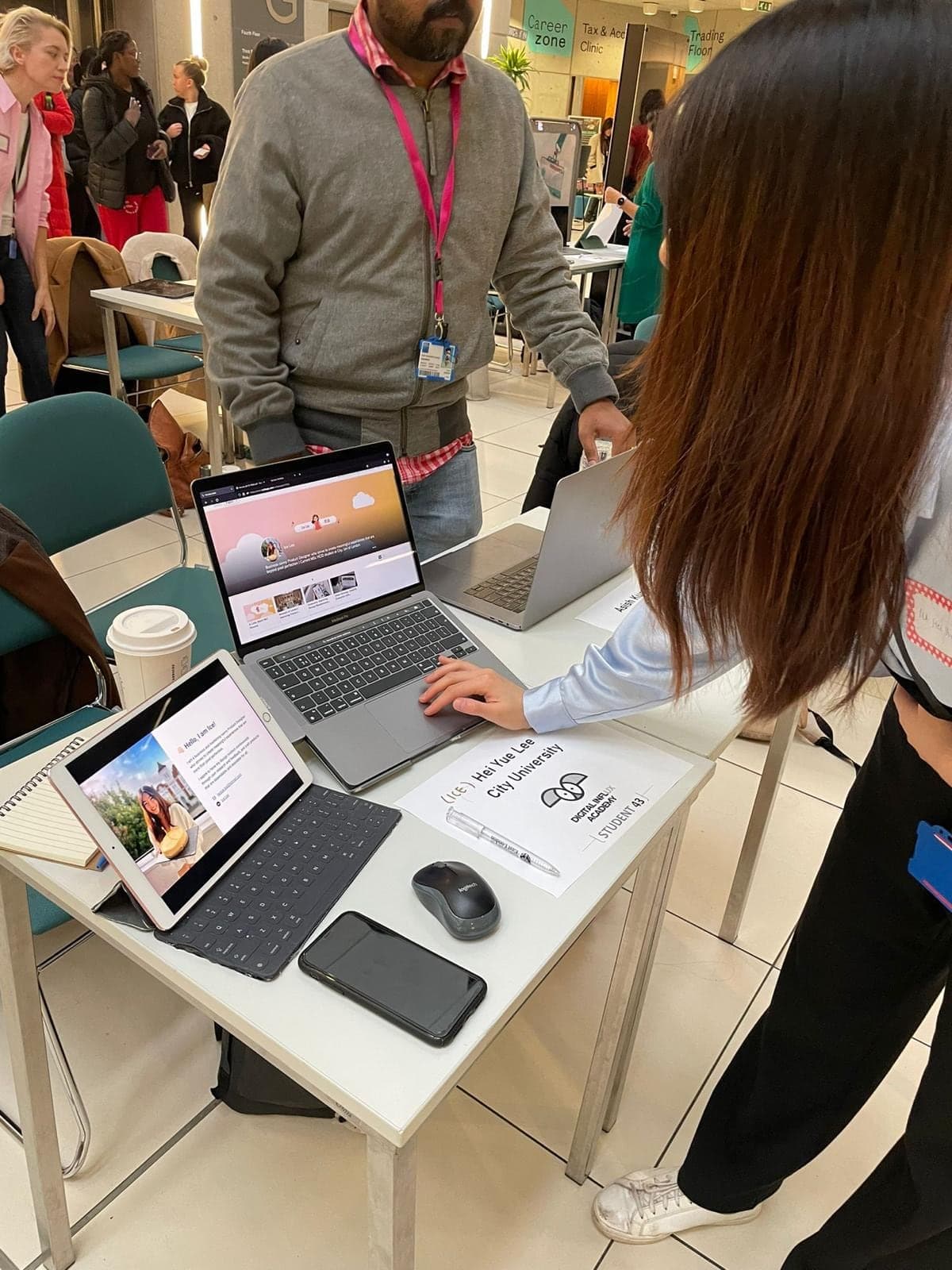 A Digital Influx Academy student from City University presenting her portfolio on a laptop, beside her academy name card.