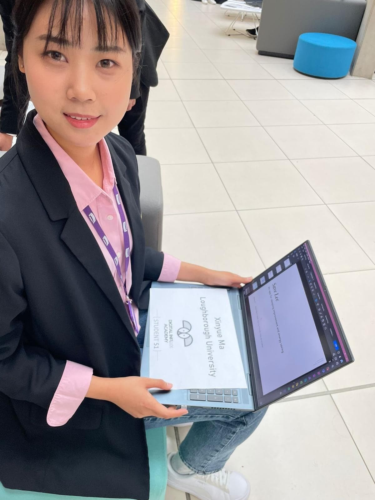 A Digital Influx Academy student from Loughborough University holding her laptop and project card.