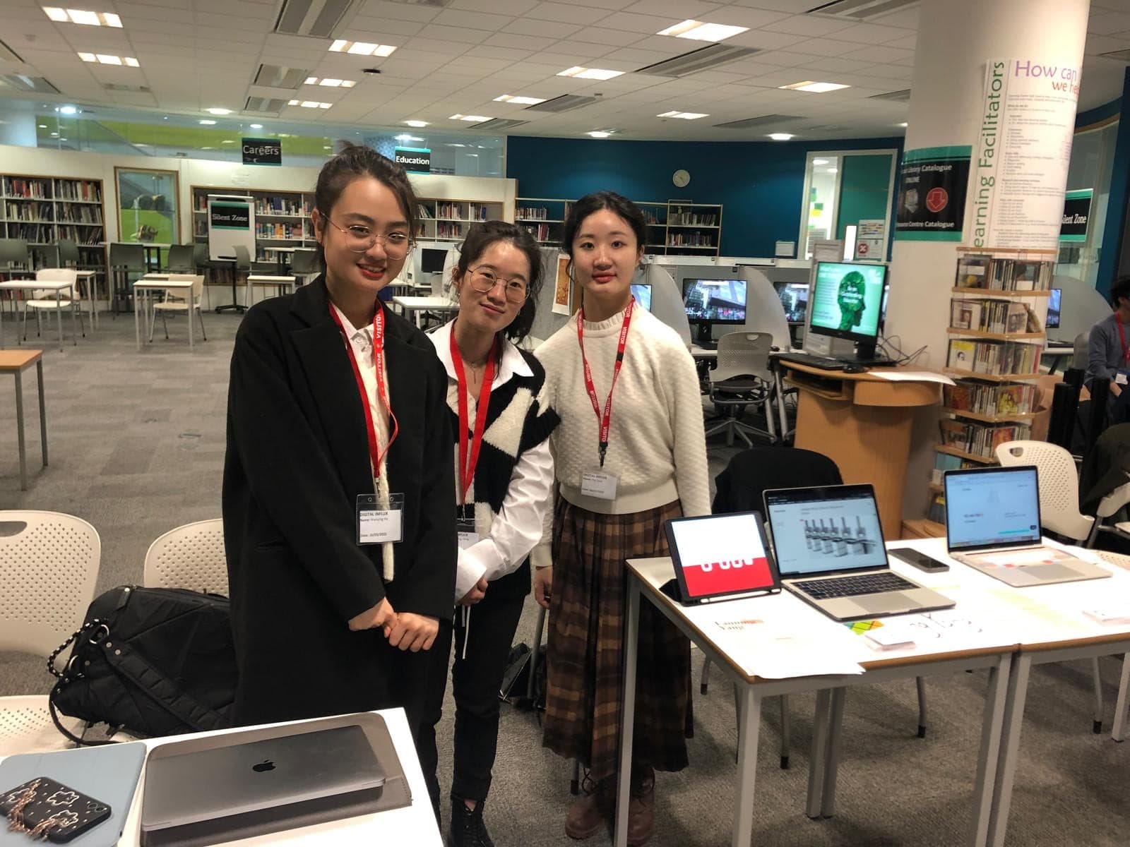 Three Digital Influx Academy students wearing event badges beside their project laptops.