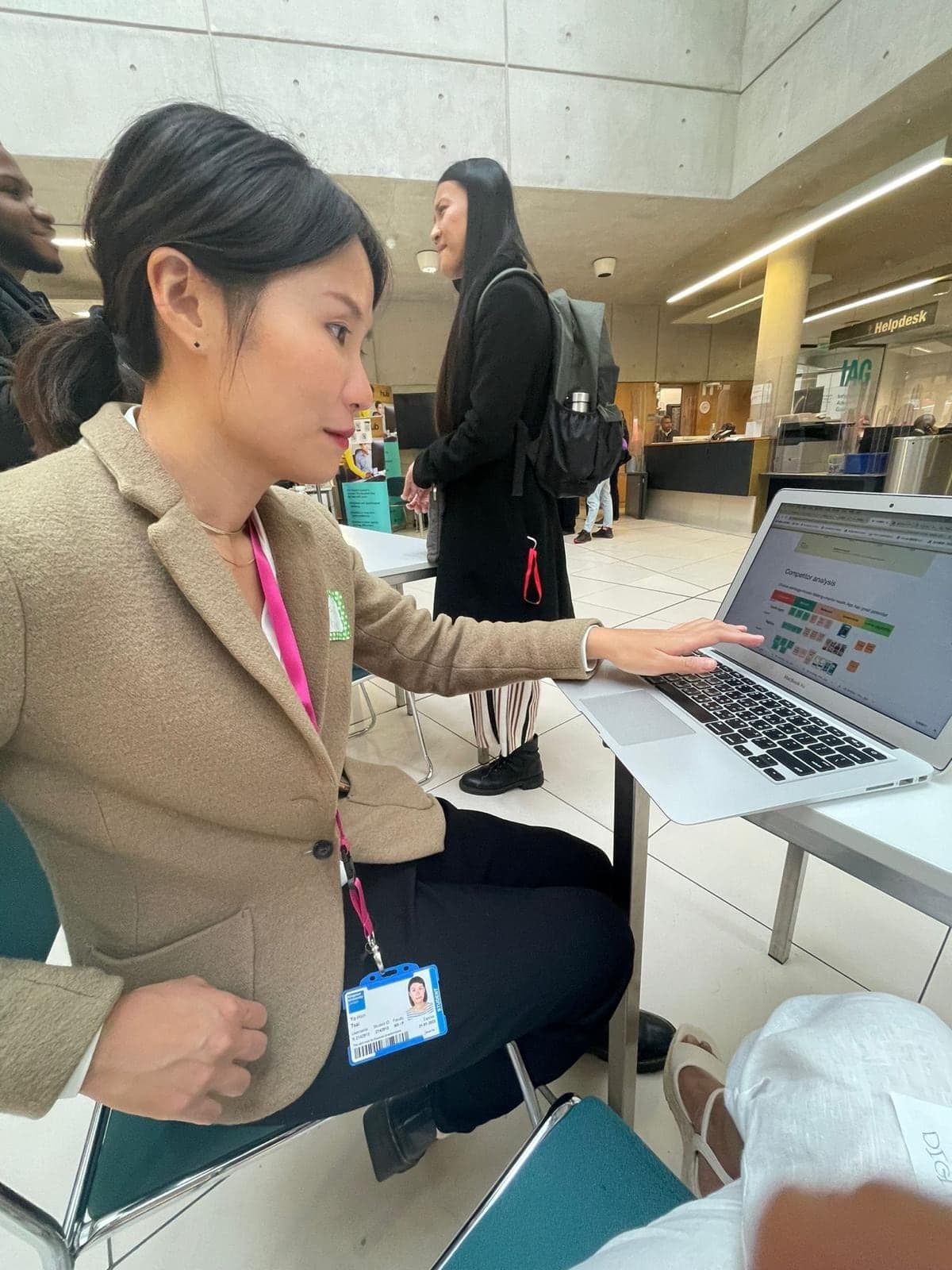A student talking through a competitor analysis on her laptop at an academy showcase.