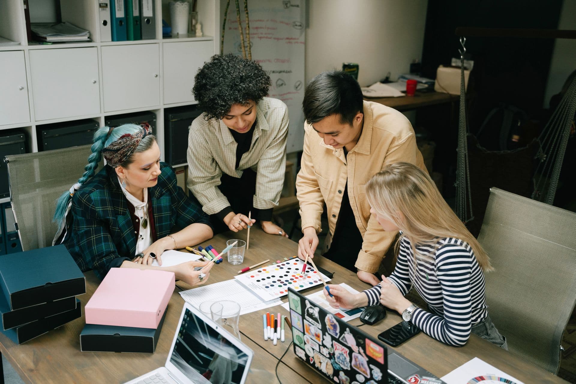 A mentor working with a young team around a table.